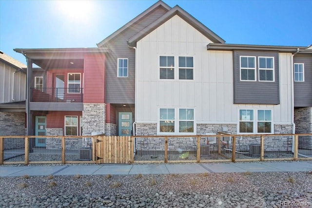 multi unit property with central air condition unit, stone siding, and fence