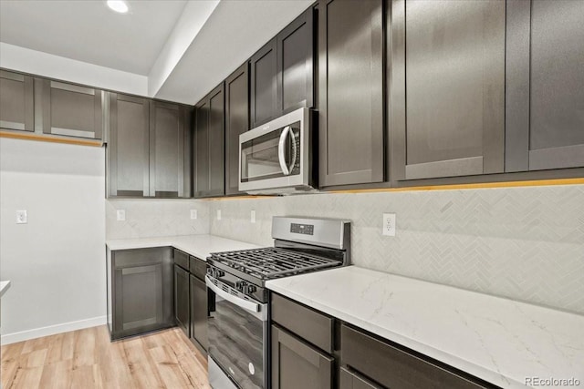 kitchen featuring tasteful backsplash, light stone countertops, light wood-type flooring, and stainless steel appliances
