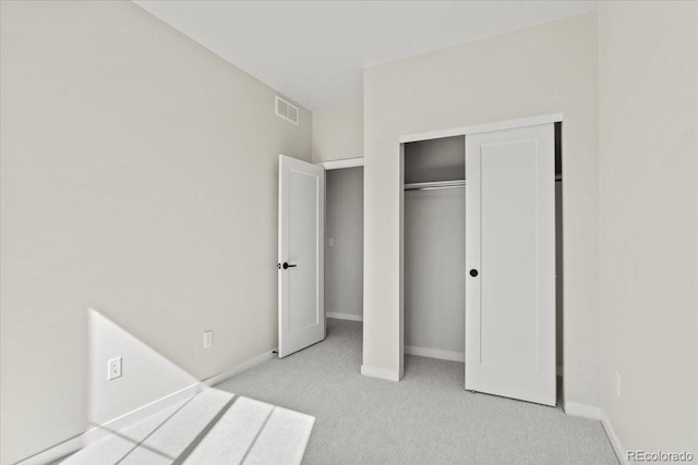 unfurnished bedroom featuring a closet, visible vents, light colored carpet, and baseboards