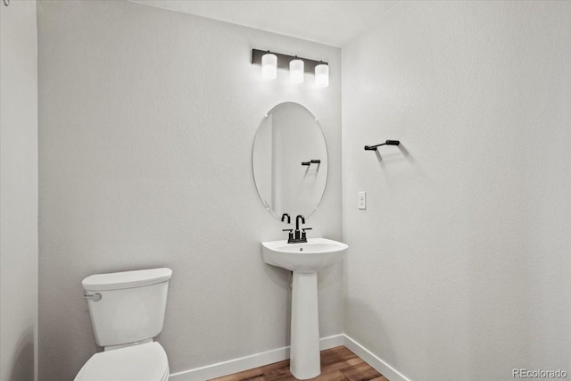 bathroom with baseboards, toilet, and wood finished floors