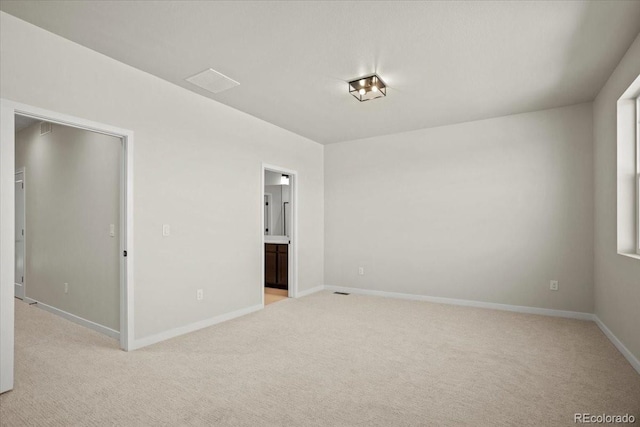 spare room featuring baseboards and light carpet
