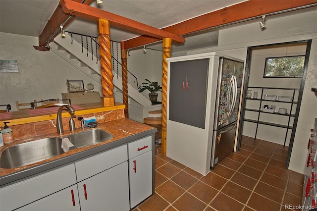 10 Baca Meadows Townhome Rd, Crestone, CO 81131 - kitchen with refrigerator, white cabinetry, dark tile patterned floors, rail lighting, and beamed ceiling