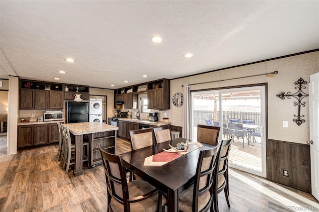 dining area with stacked washer / dryer, light wood-style floors, recessed lighting, crown molding, and wainscoting