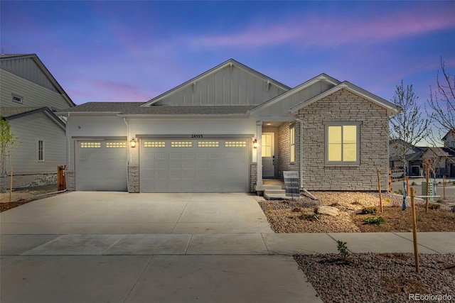 24593 E 34th Ave, Aurora, CO 80019 - view of front of house with board and batten siding, a garage, driveway, and stone siding