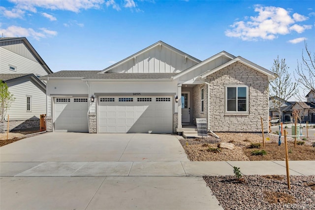 24593 E 34th Ave, Aurora, CO 80019 - view of front of property featuring board and batten siding, a garage, stone siding, and concrete driveway