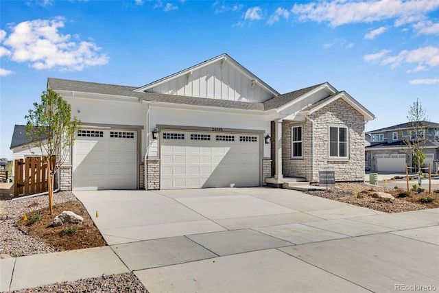 24593 E 34th Ave, Aurora, CO 80019 - view of front of house with board and batten siding, an attached garage, stone siding, and driveway