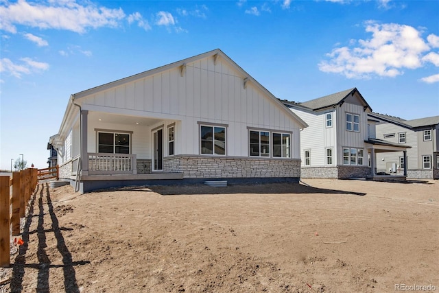 24593 E 34th Ave, Aurora, CO 80019 - back of house with board and batten siding, stone siding, covered porch, and fence