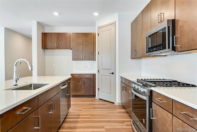 24593 E 34th Ave, Aurora, CO 80019 - kitchen with appliances with stainless steel finishes, a sink, light wood finished floors, light countertops, and tasteful backsplash