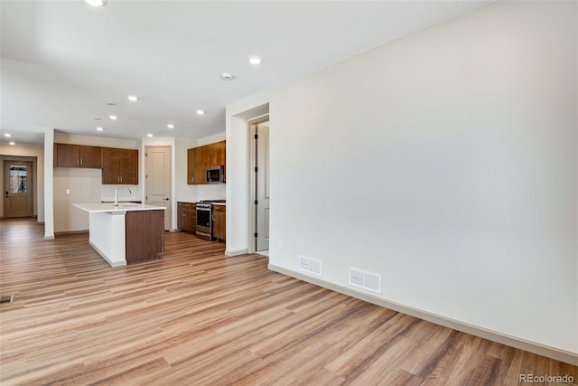 24593 E 34th Ave, Aurora, CO 80019 - kitchen featuring appliances with stainless steel finishes, light wood finished floors, light countertops, a center island with sink, and recessed lighting