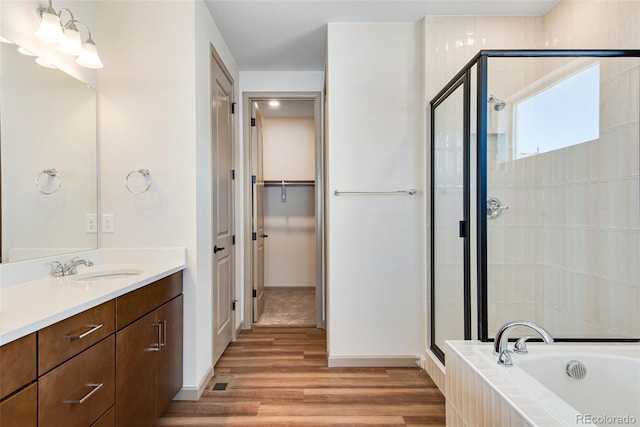 24593 E 34th Ave, Aurora, CO 80019 - full bathroom featuring a stall shower, wood finished floors, vanity, a walk in closet, and tiled tub