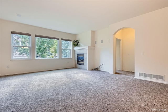 7831 S Addison Way, Aurora, CO 80016 - unfurnished living room with arched walkways, carpet, and a tile fireplace