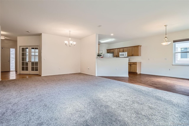 7831 S Addison Way, Aurora, CO 80016 - unfurnished living room with dark colored carpet, a chandelier, dark wood-type flooring, and french doors