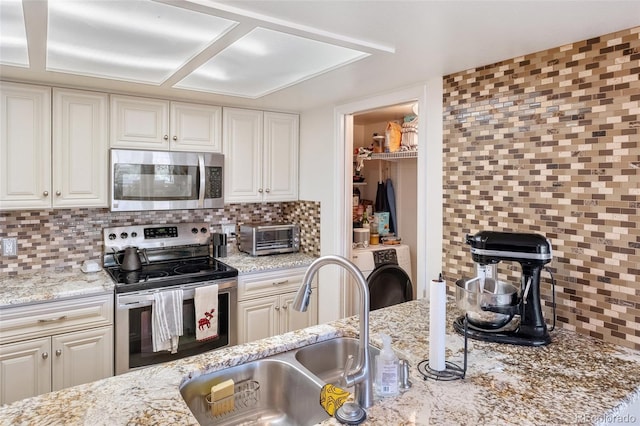 kitchen with stainless steel appliances, washer / dryer, sink, and decorative backsplash