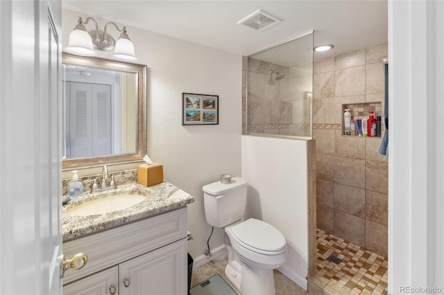 bathroom featuring vanity, toilet, and tiled shower