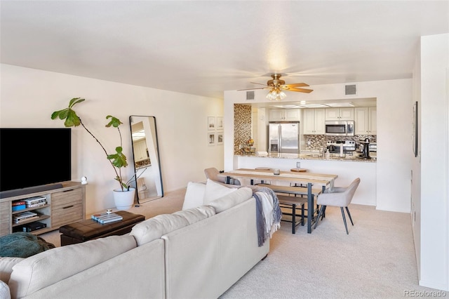 living room with visible vents, a ceiling fan, and light colored carpet