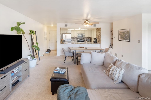 living room with a ceiling fan, light colored carpet, and visible vents