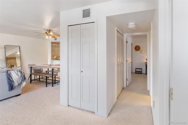 hall featuring visible vents and light colored carpet