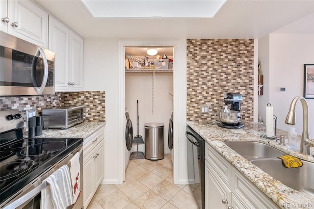 kitchen featuring a toaster, white cabinets, a sink, stainless steel appliances, and backsplash