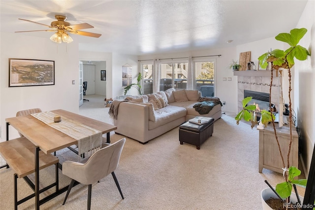 living area with light carpet, a fireplace, and a ceiling fan