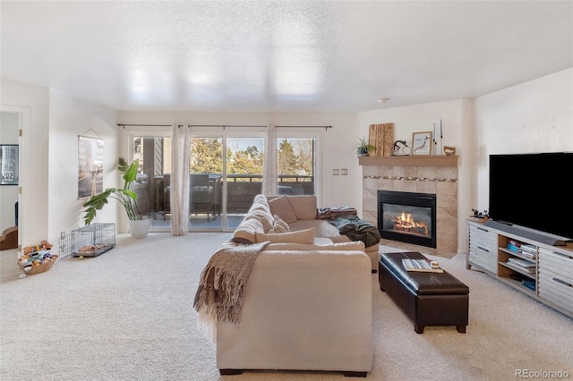 living area with carpet, a textured ceiling, and a tiled fireplace