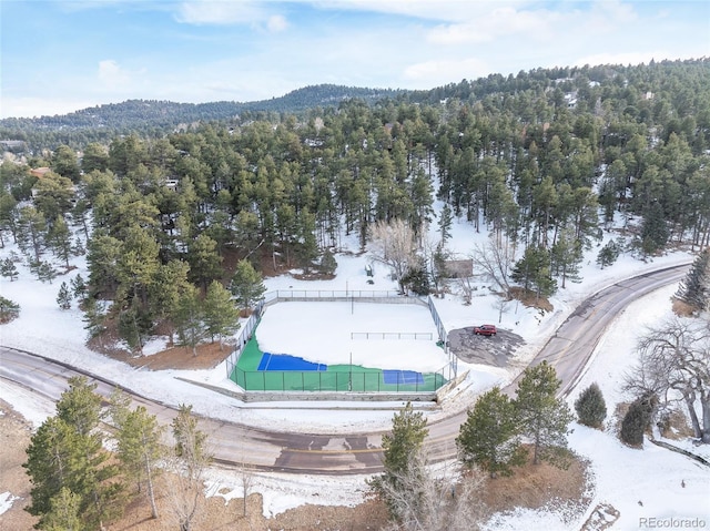 snowy aerial view with a wooded view