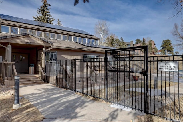 view of gate featuring roof mounted solar panels and fence