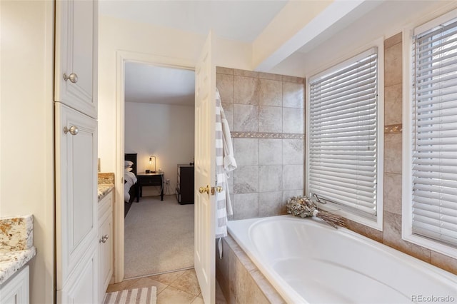 ensuite bathroom featuring tile patterned flooring, tiled tub, connected bathroom, and vanity