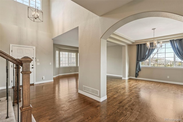 entryway with visible vents, arched walkways, a chandelier, and plenty of natural light