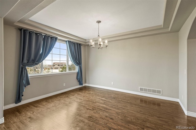 unfurnished room with baseboards, an inviting chandelier, visible vents, a raised ceiling, and wood finished floors