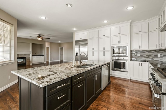 kitchen featuring a sink, white cabinets, a ceiling fan, and built in appliances