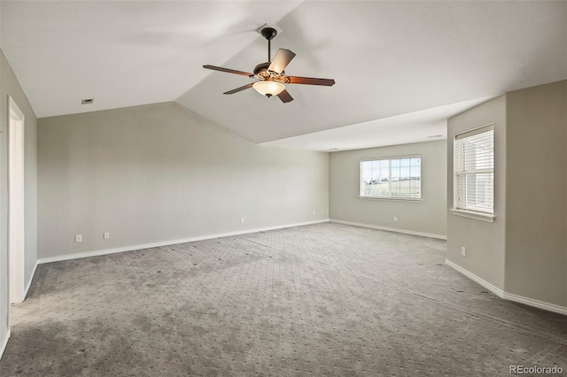 carpeted empty room featuring baseboards, visible vents, vaulted ceiling, and a ceiling fan