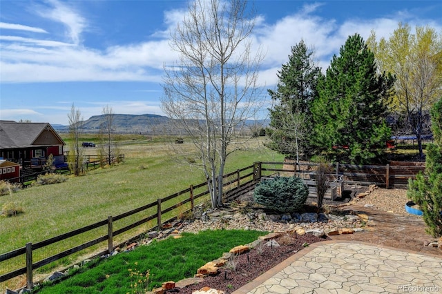 view of yard with a rural view, fence, and a mountain view