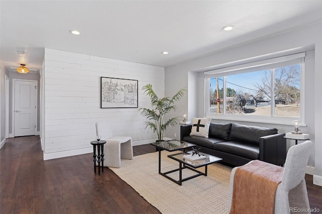 living room with an accent wall, recessed lighting, baseboards, and wood finished floors