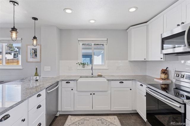 kitchen with appliances with stainless steel finishes, a healthy amount of sunlight, a sink, and white cabinetry