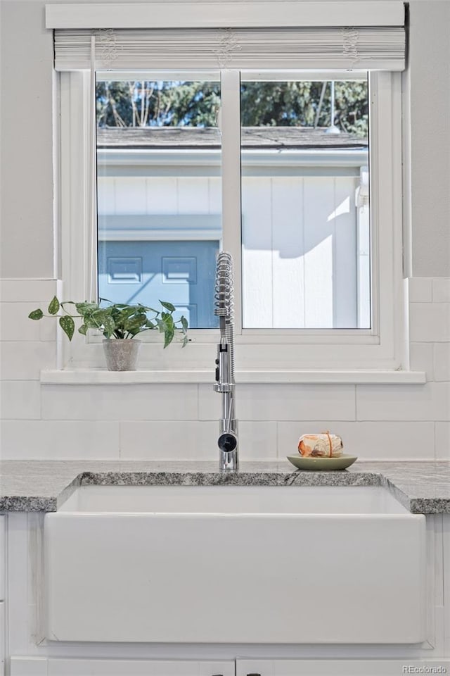 room details featuring light stone counters, a sink, and white cabinetry