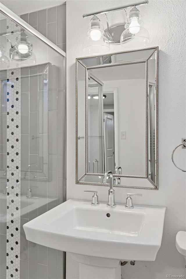 full bathroom featuring a stall shower, a sink, and toilet