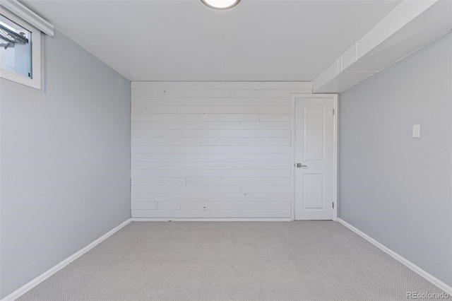 empty room featuring carpet floors, wooden walls, and baseboards