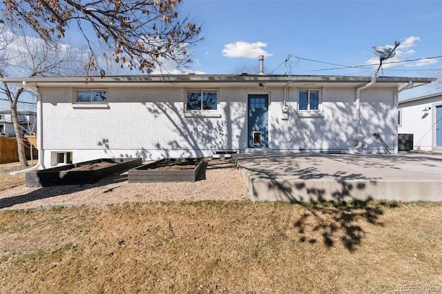 back of property with brick siding and a vegetable garden