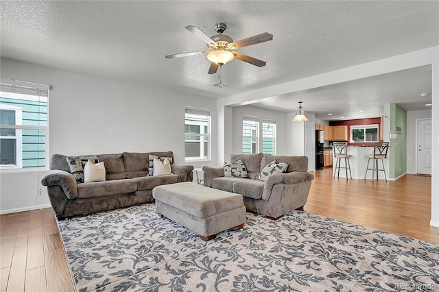 18947 E 57th Pl, Denver, CO 80249 - living room featuring light wood finished floors, a ceiling fan, and a textured ceiling