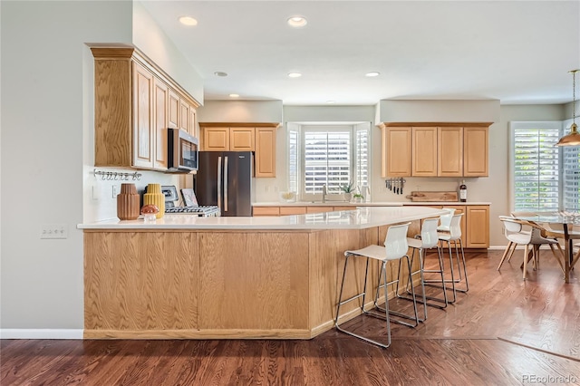 kitchen with black fridge, light brown cabinets, dark hardwood / wood-style flooring, kitchen peninsula, and stove