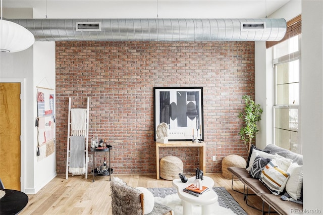 living room with brick wall and light wood-type flooring