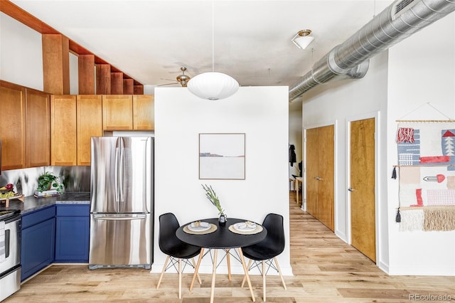 kitchen featuring stainless steel fridge, a towering ceiling, and light hardwood / wood-style flooring