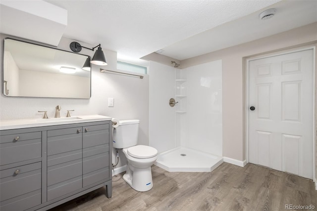 bathroom with a textured ceiling, vanity, a shower, hardwood / wood-style flooring, and toilet