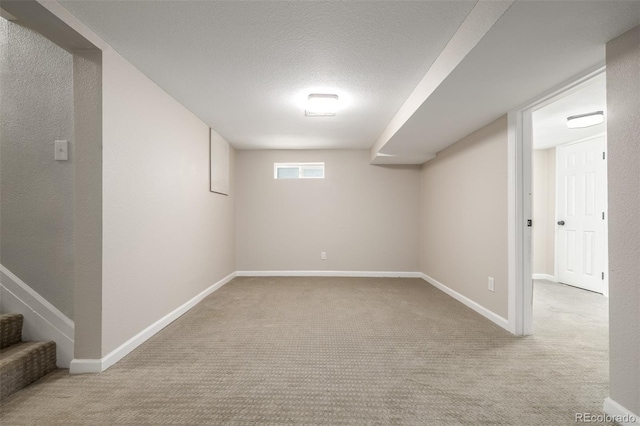 basement featuring light carpet and a textured ceiling