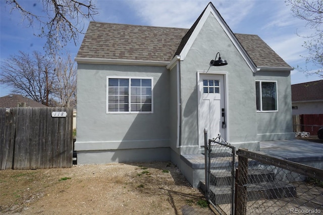 back of property with fence, a shingled roof, and stucco siding