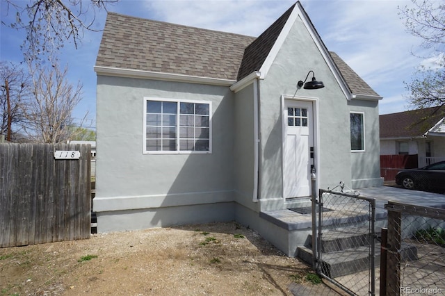 view of front of home featuring stucco siding, fence, and a shingled roof