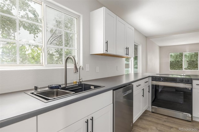 kitchen with stainless steel appliances, white cabinets, a sink, and light wood-style flooring