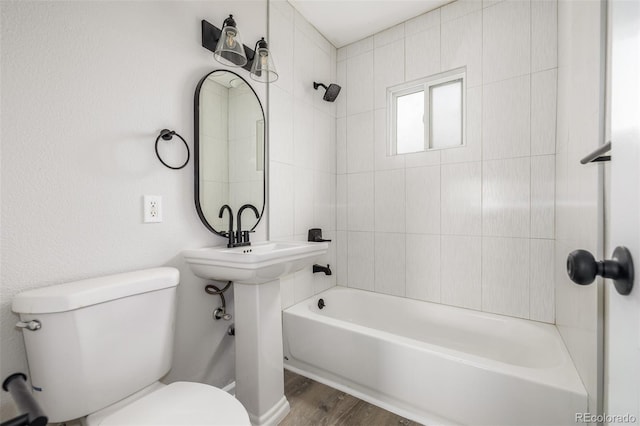 bathroom with toilet, wood finished floors, and bathing tub / shower combination