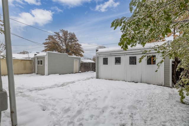yard layered in snow featuring fence and an outbuilding