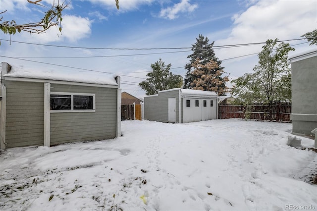 snowy yard with an outbuilding and fence